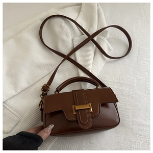 Close-up of brown vintage mini handbag with glossy finish and gold buckle on white fabric
