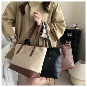 Three minimalist large capacity tote bags in beige, black and brown displayed on a sofa
