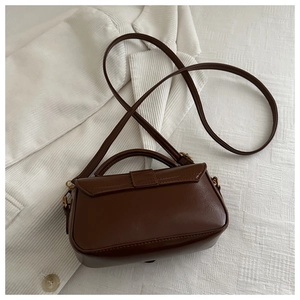 Detail shot of a dark brown glossy vintage PU leather small square handbag and strap