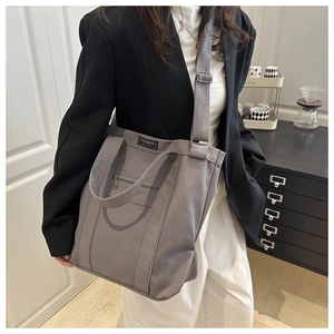 Detail of deep grey canvas tote bag with adjustable shoulder strap and fashion label