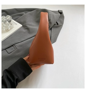 Detail of caramel leather handbag featuring embossed Fashion Bags text and soft texture