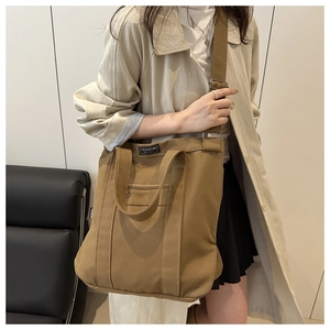 Detail of dark khaki canvas tote bag featuring adjustable strap and fashion label