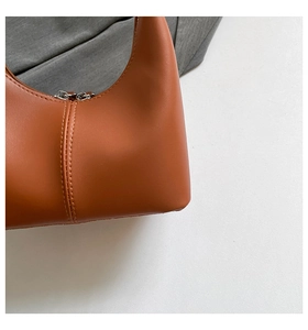 Close-up of caramel leather hobo bag featuring dual stitching and silver zipper detail