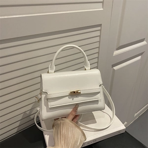 Minimalist white faux leather handbag with gold twist lock and circular top handle