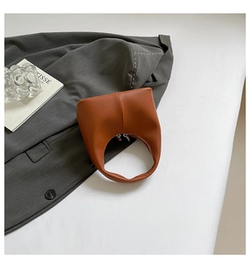 Detail of caramel brown leather handbag with integrated handle and dual silver zippers