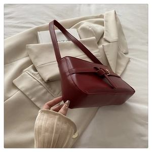 Detail of the elegant dark red leather knot clasp on a minimalist underarm shoulder bag