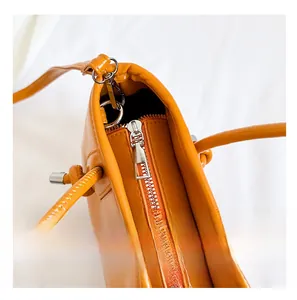 Close-up of a bright orange bucket bag showing the smooth silver metal zipper and PU leather texture