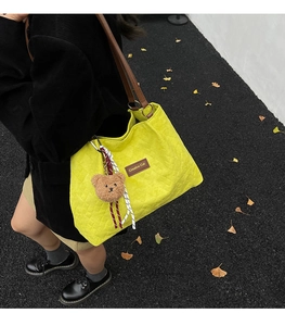 Detail of yellow corduroy tote bag with Creative Cat label and cute bear charm
