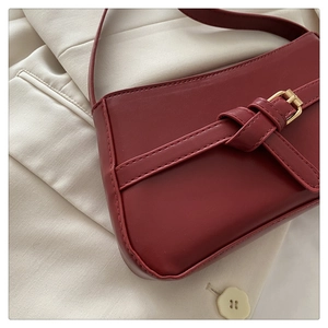 Detailed close-up of dark red PU leather shoulder bag with gold square buckle and stitching
