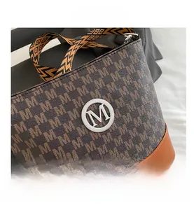 Detail of monogrammed brown bucket bag with wide patterned strap and silver metal logo