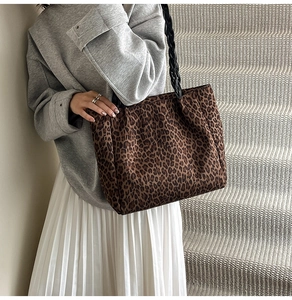 Detail of trendy leopard print tote bag featuring textured fabric and woven shoulder straps