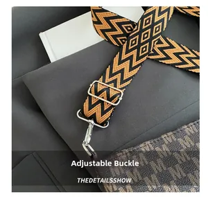 Detail of adjustable woven shoulder strap with silver buckle and monogram letter pattern
