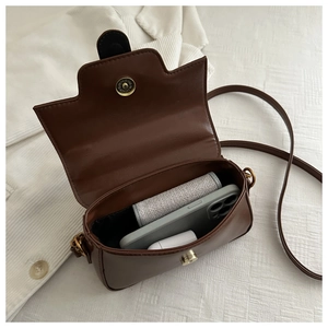 Brown saddle bag interior detail showing metal magnetic clasp and daily essentials storage