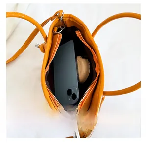 Top view of bright orange bucket bag interior showing capacity for phone and cosmetics
