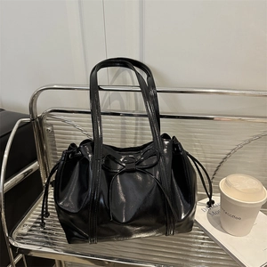 Elegant black glossy tote bag with ribbon bow detail and drawstring closure design
