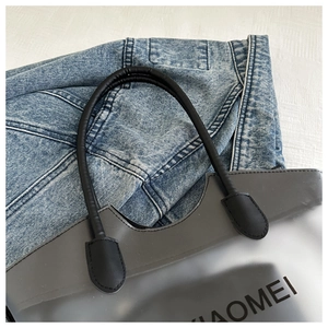 Vue détaillée du sac cabas gris translucide avec anses noires sur tissu denim