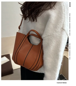 Detail of caramel crossbody bucket bag showing smooth texture and vertical black stripes