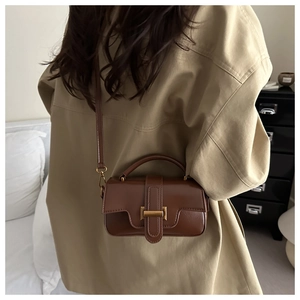 Brown vintage leather handbag shown on model featuring retro gold buckle and crossbody strap