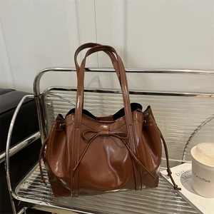 Chic brown patent leather tote bag with bow detail and drawstring for daily commuting
