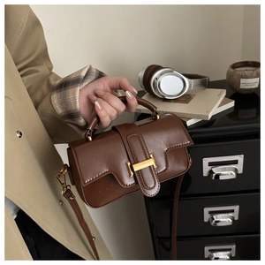 Detail of vintage brown leather bag showing gold buckle and texture in lifestyle setting