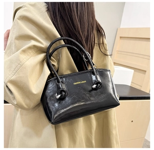 Detail of black glossy handbag with gold logo lettering and double round handles