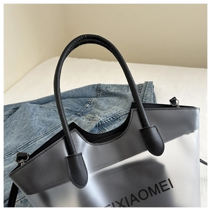 Détail d'un sac cabas en PVC noir translucide avec poignées en cuir et texte XIAOMEI
