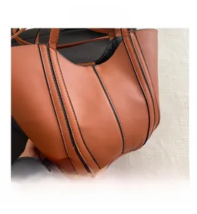 Detailed close-up of brown faux leather tote bag showing black vertical stitching details