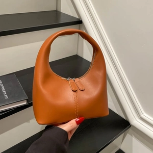 Chic caramel leather crescent handbag with sleek arch handle and dual zipper design