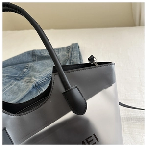 Vue détaillée du sac cabas en PVC gris semi-transparent avec poignées en cuir noir