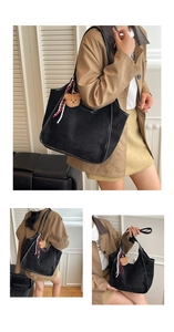Detail of black suede tote bag featuring plush bear charm and striped ribbon accent
