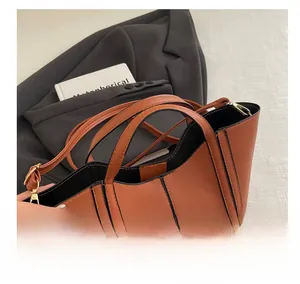 Detailed view of brown leather bucket bag with black edge painting and dual handles