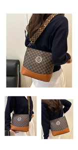 Detail of crossbody bag with brown M-pattern, caramel leather, and ethnic woven strap