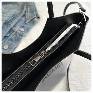 Vue de dessus du sac seau en cuir mat noir montrant la fermeture éclair et le logo détaillé