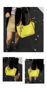 Detail of yellow canvas bucket bag with brown leather handles and a cute bear charm