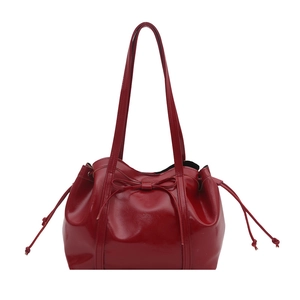 Fashionable dark red glossy leather shoulder bag with drawstring bow detail and sleek straps