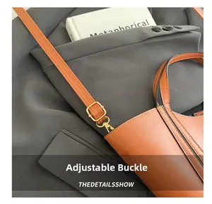 Detail of adjustable shoulder strap with golden buckle on a brown leather bucket bag