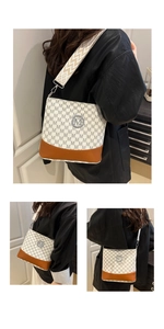 Detailed view of bucket bag with monogram print, brown leather base, and wide woven strap