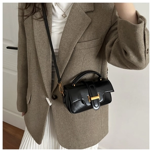 Détail d'un mini sac en cuir noir avec une boucle dorée et une poignée élégante