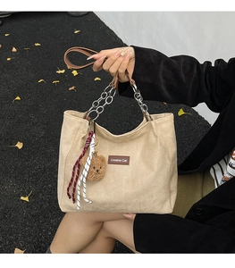 Détail d'un cabas en velours côtelé beige avec breloque ours et étiquette en cuir
