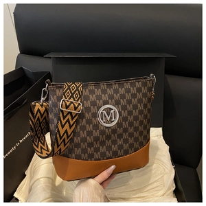 Close-up of contrast stitching shoulder bag with metal M-logo and geometric strap