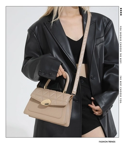 Détail d'un sac à main matelassé beige avec boucle dorée et bandoulière en cuir