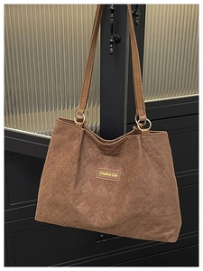 Detail of dark brown quilted suede tote bag with Creative Cat label and gold hardware