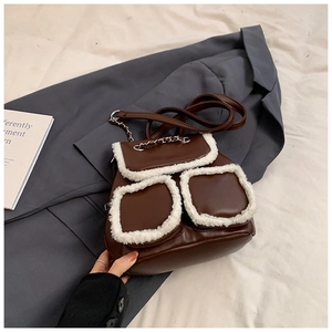 Detail of dark brown backpack with white faux shearling trim and silver chain