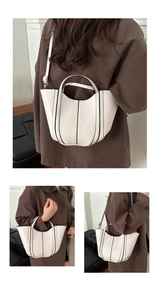 Detail of cream white leather bucket bag featuring contrasting black trim and gold hardware