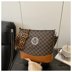 Detail of a brown monogram bucket bag featuring a gold M logo and geometric woven strap