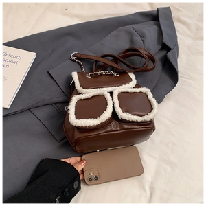 Detailed close-up of brown faux leather mini backpack with white plush trim and chain strap