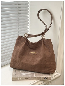 Detailed view of dark brown quilted tote bag with diamond stitching and leather tag