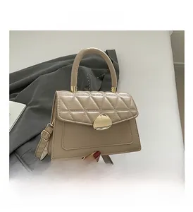 Détail du sac beige matelassé avec fermoir triangle doré et texture façon crocodile