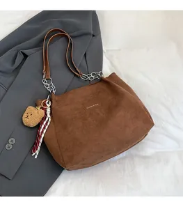 Détail du sac fourre-tout en velours côtelé marron avec bandoulière chaîne et breloque ours