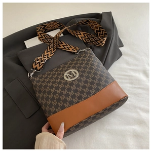 Close-up of brown monogram bucket bag with patterned strap and metal M logo detail